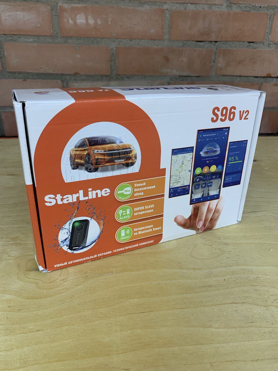 Упаковка StarLine S96 V2 на столе у кирпичной стены в боксе